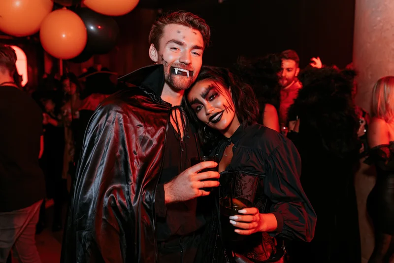 Couple in vampire costumes posing together at a halloween party in a nightclub