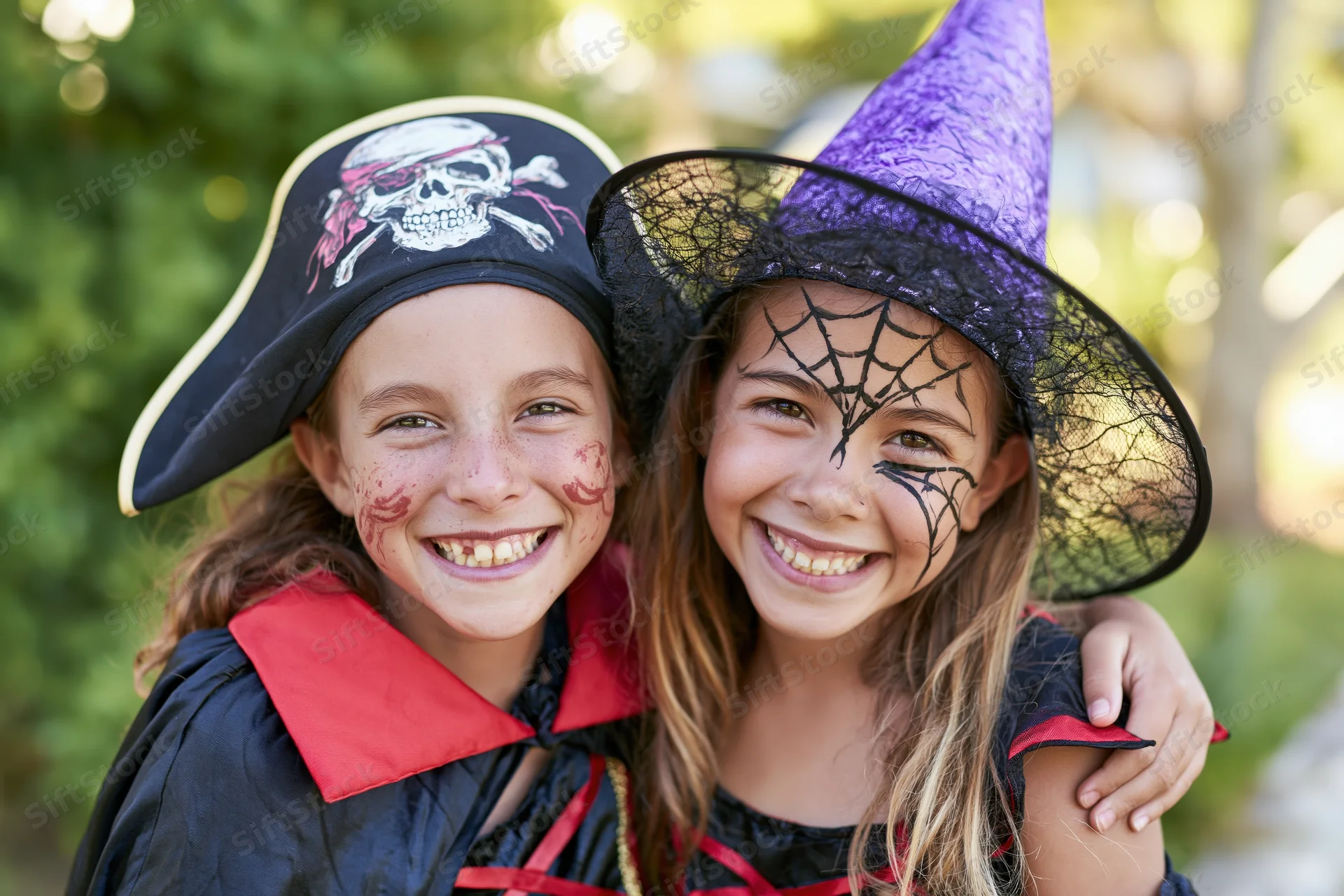 Two young girls in pirate and witch costumes smiling together outdoors