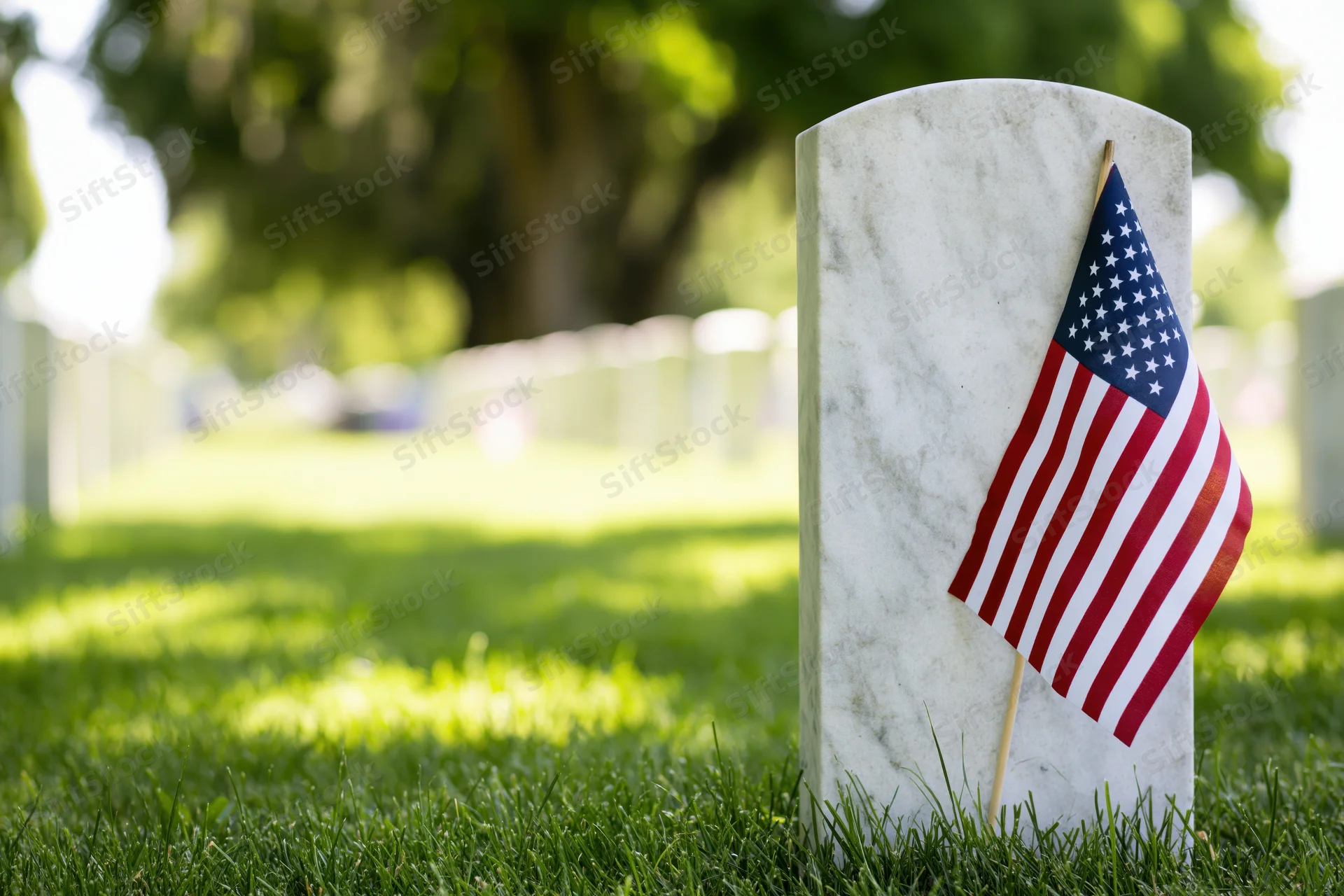 American flag placed on white marble headstone in grassy veterans cemetery