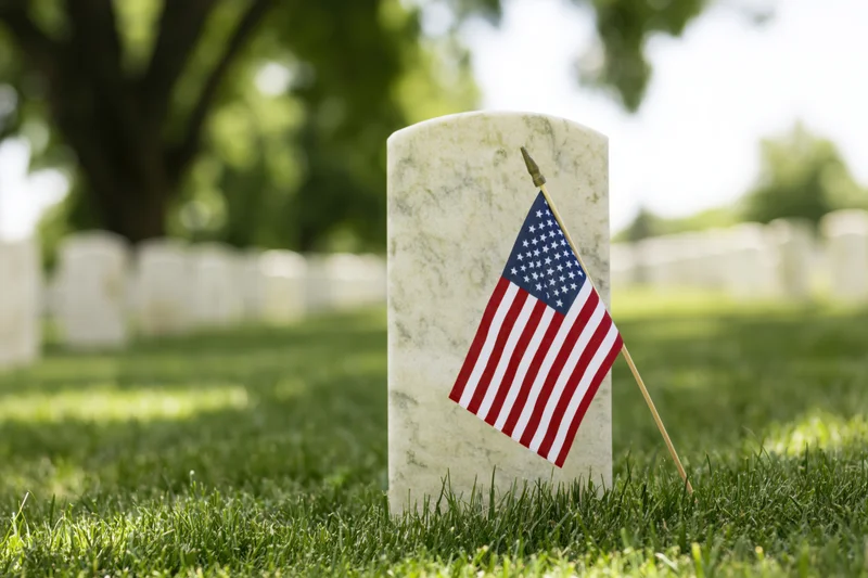 American flag placed at white marble headstone in veterans cemetery grassy field
