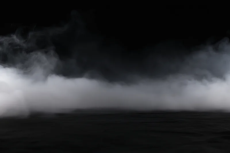 White smoke spreading low across a dark studio floor