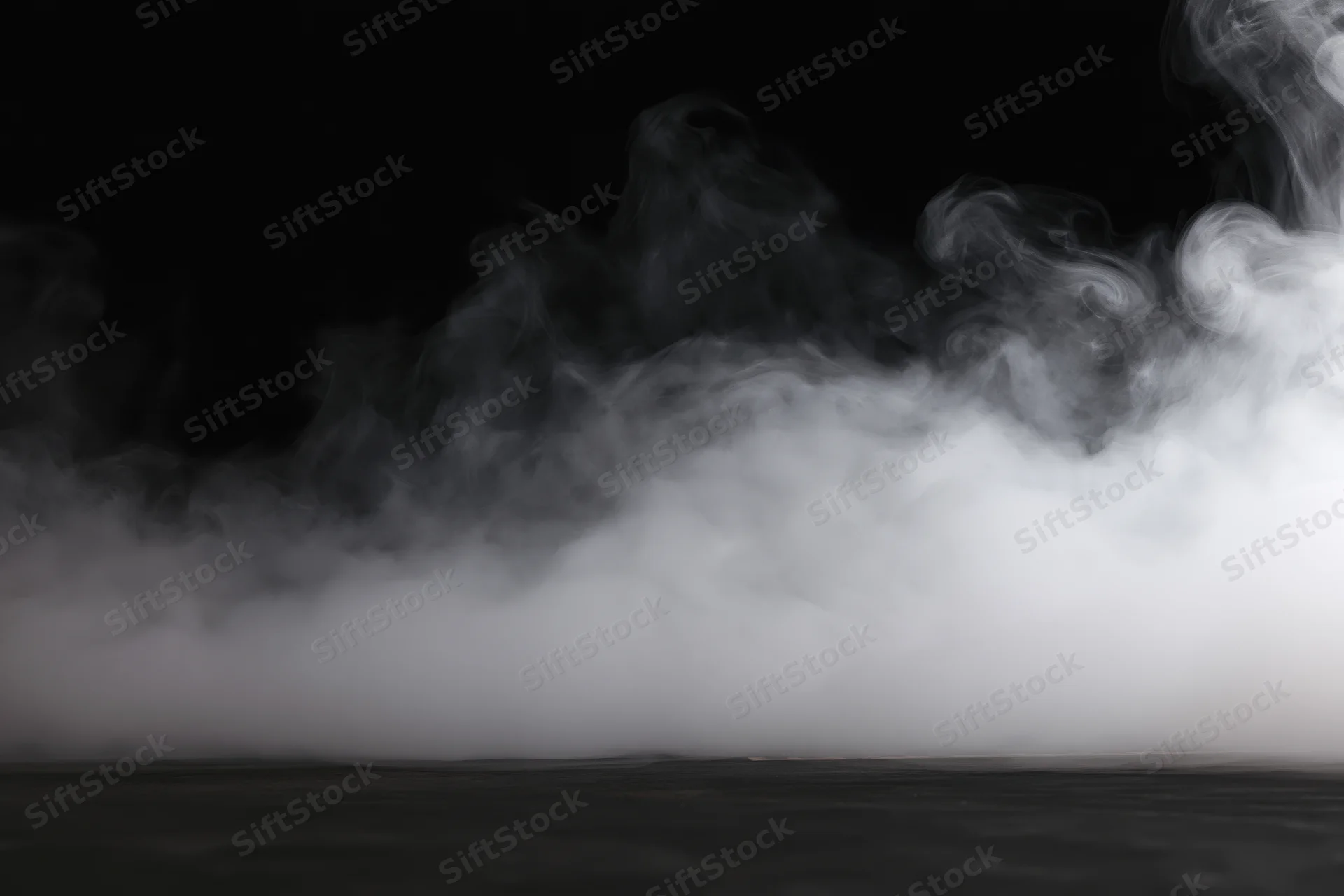 White smoke spreading low across a dark studio floor