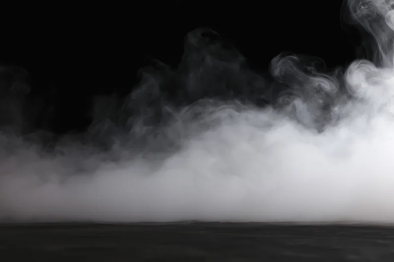 White smoke spreading low across a dark studio floor