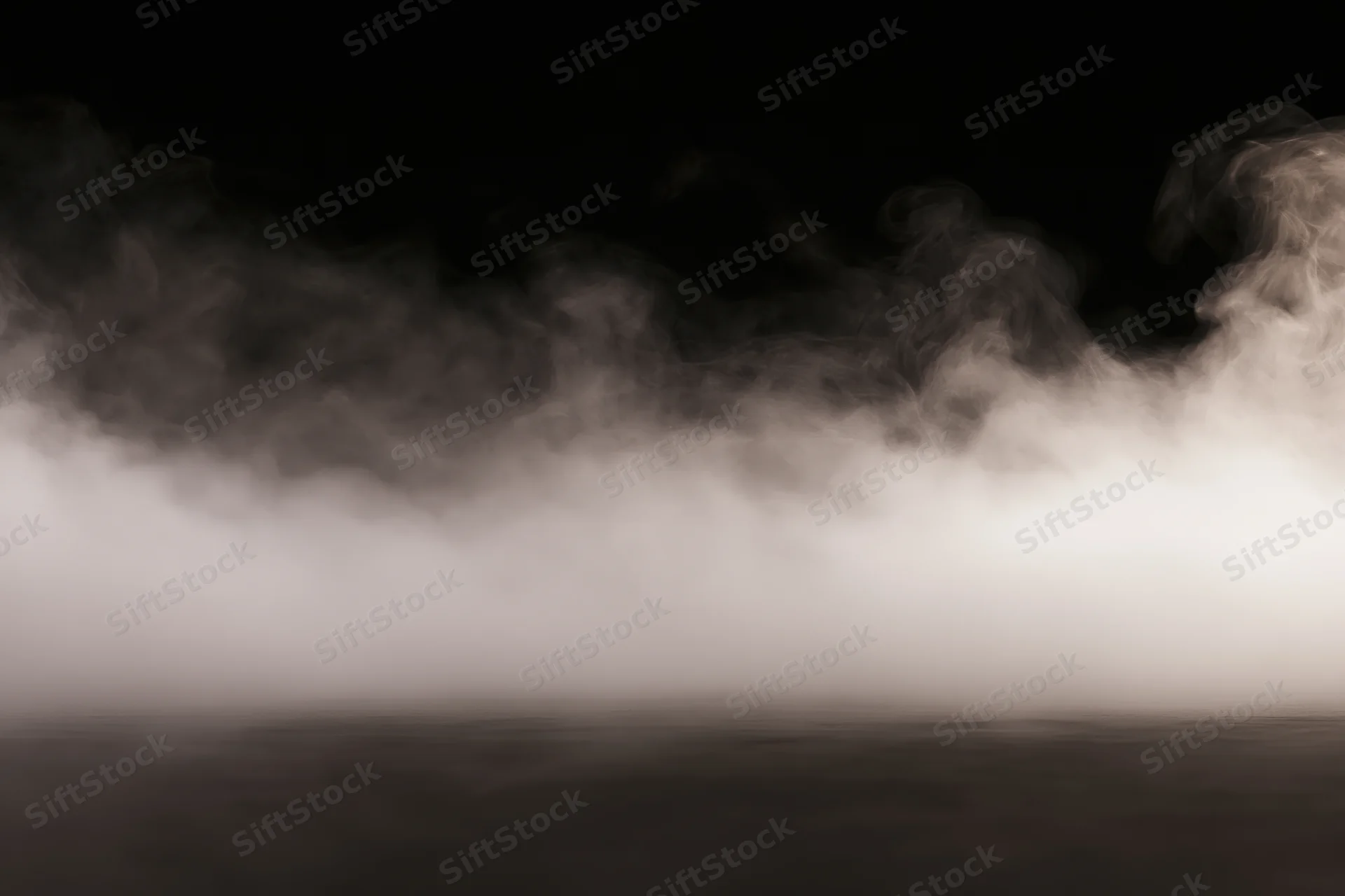 White smoke spreading low across a dark studio floor