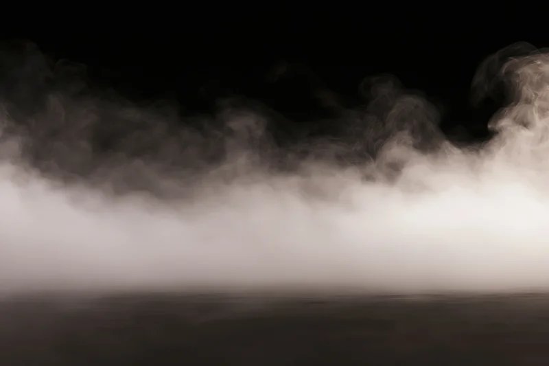 White smoke spreading low across a dark studio floor