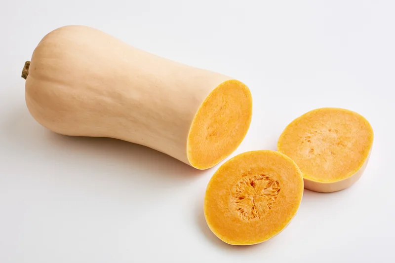Whole butternut squash with two round slices on white background