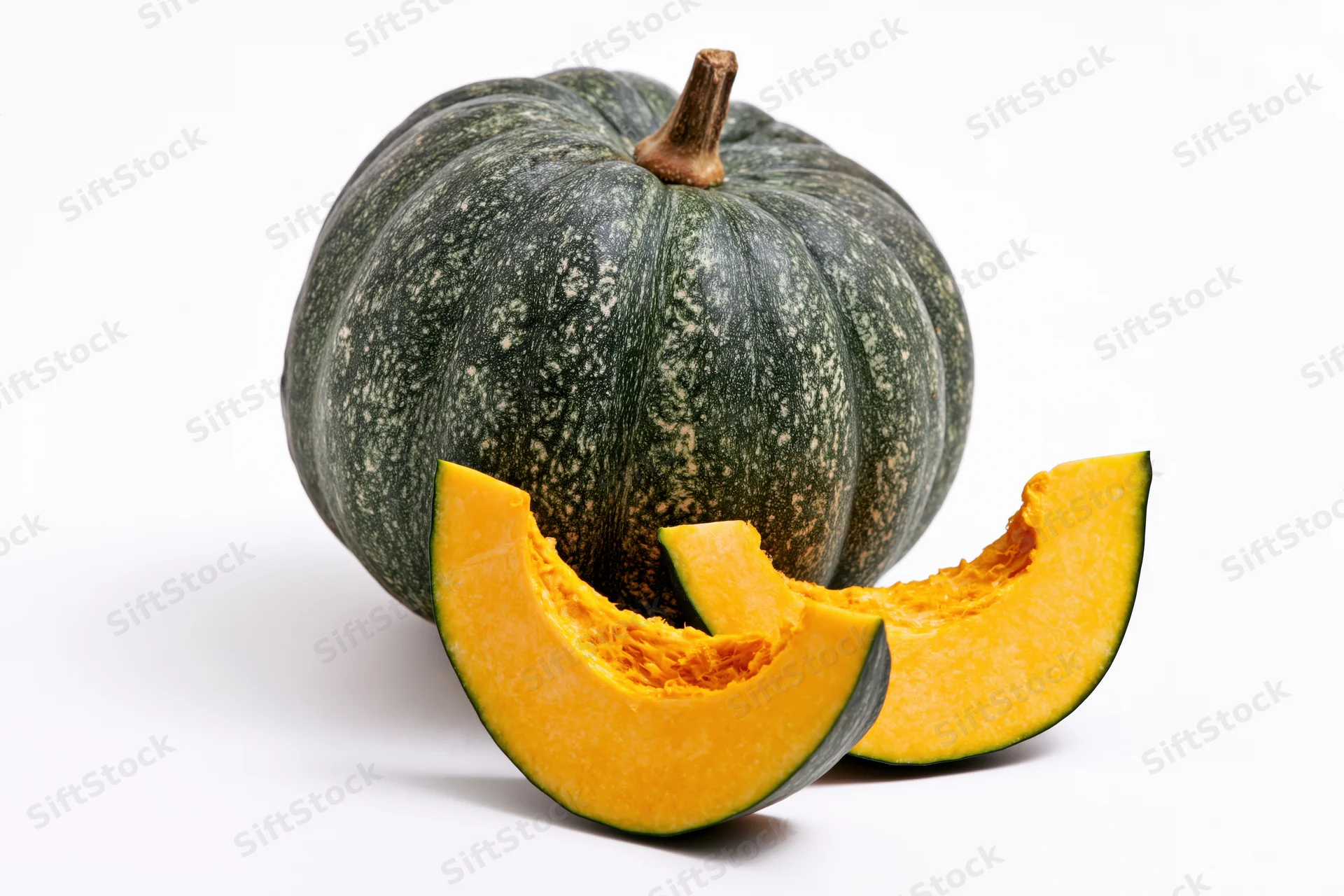 Whole kabocha squash with two cut wedge slices on white background