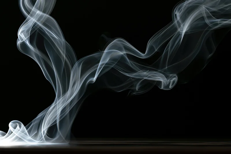 Wispy white smoke curling and rising against a black background