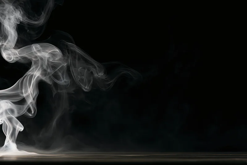 White smoke curling and rising against a black background