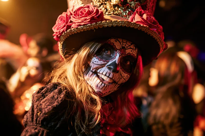 Woman with sugar skull face paint and decorative hat at a Day of the Dead celebration