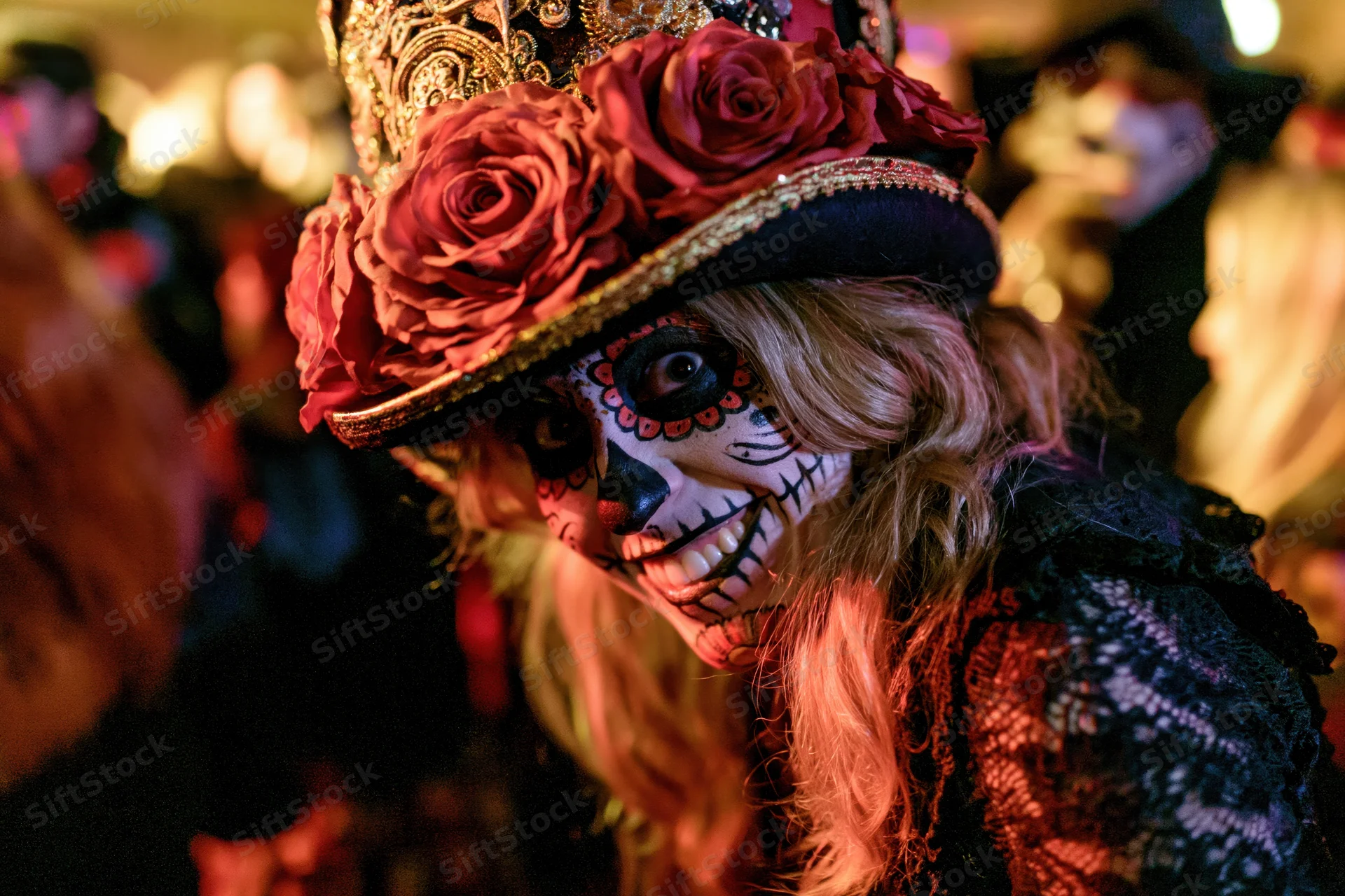 Woman with sugar skull face paint and rose-adorned hat at a Day of the Dead celebration