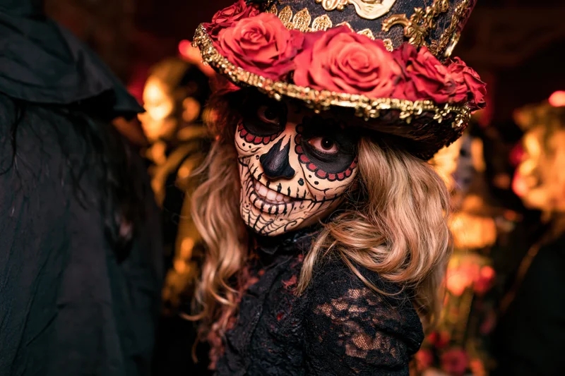 Woman with sugar skull face paint and floral hat at a Day of the Dead celebration