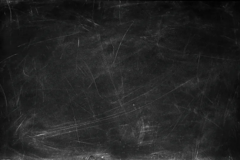 Worn blackboard surface with faint chalk smears and scratches, showing signs of frequent use in a classroom setting