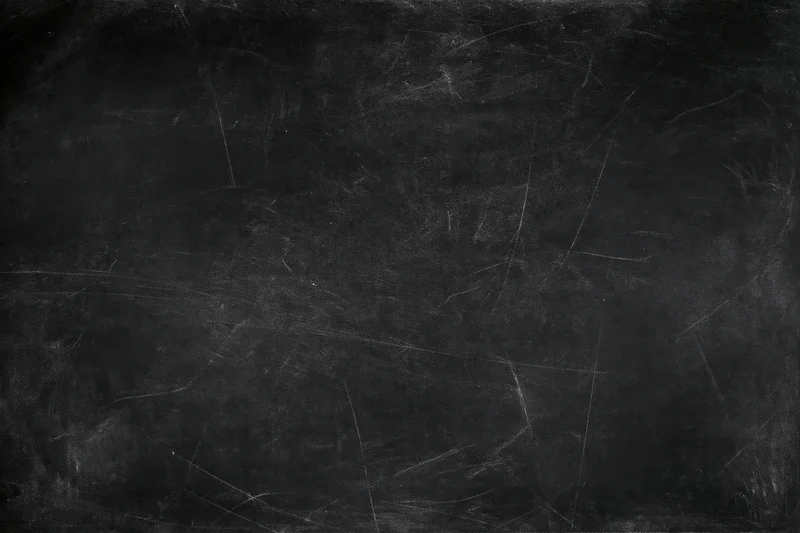 Worn blackboard surface with faint chalk smears and scratches, showing texture and residue from use