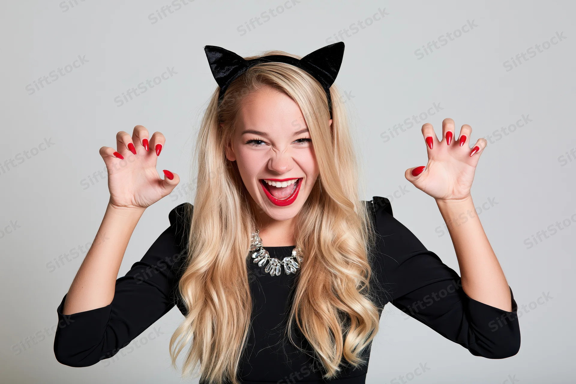 Blonde woman in cat costume smiling with raised hands and claws in studio