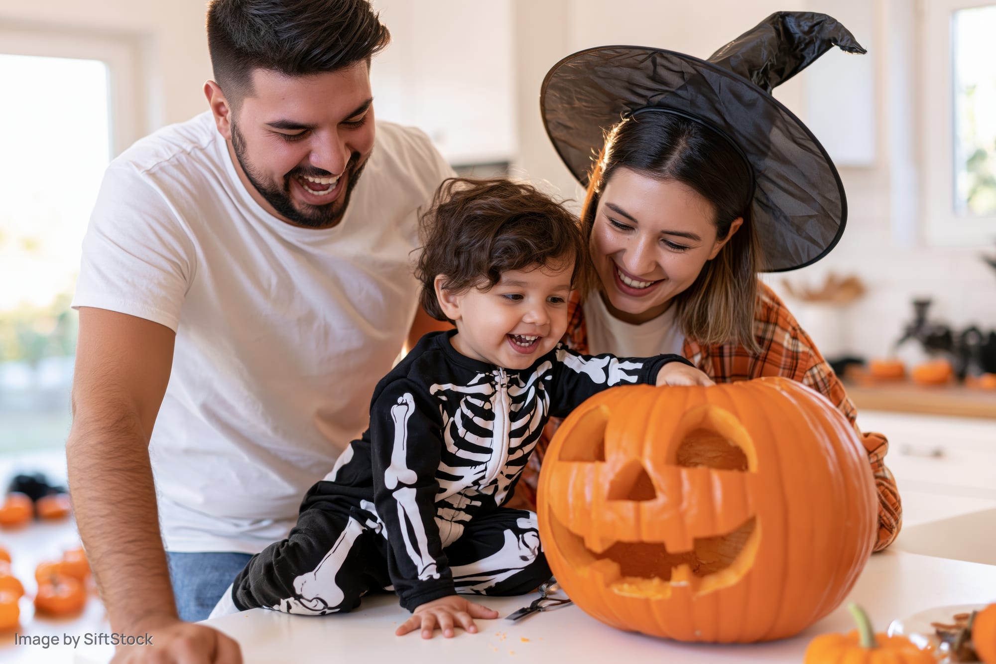 Young family carving a jack-o-lantern together in kitchen