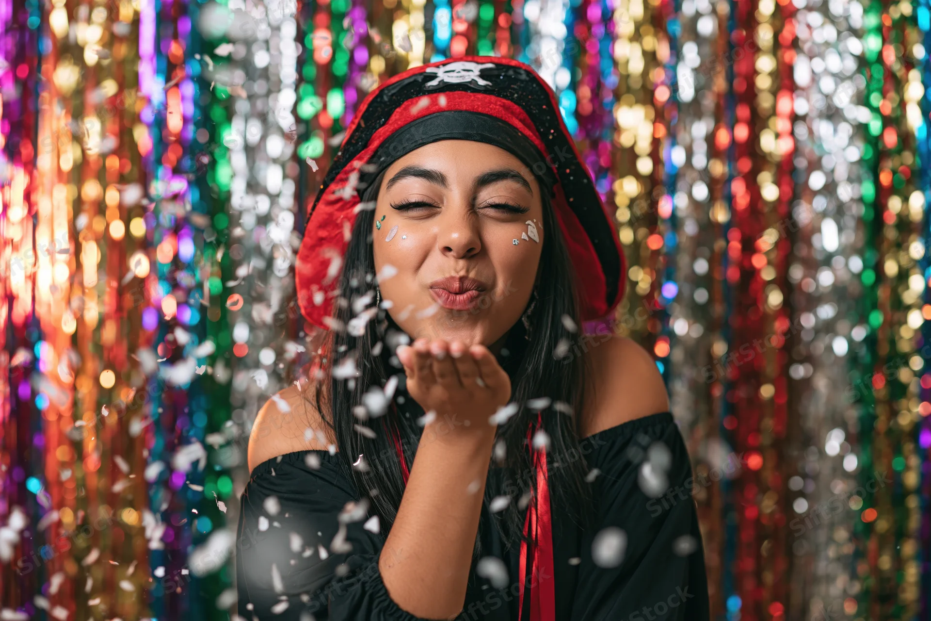 Woman in pirate costume blowing confetti against a colorful sequined backdrop