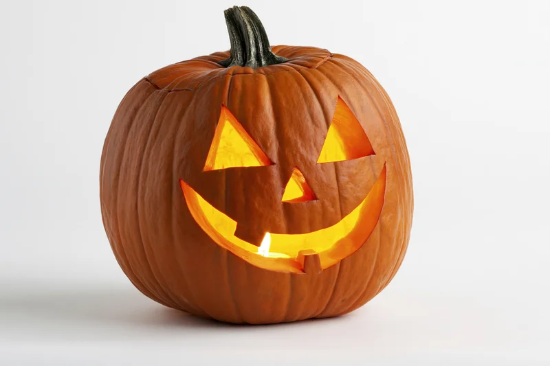 Carved pumpkin with glowing grin on white background