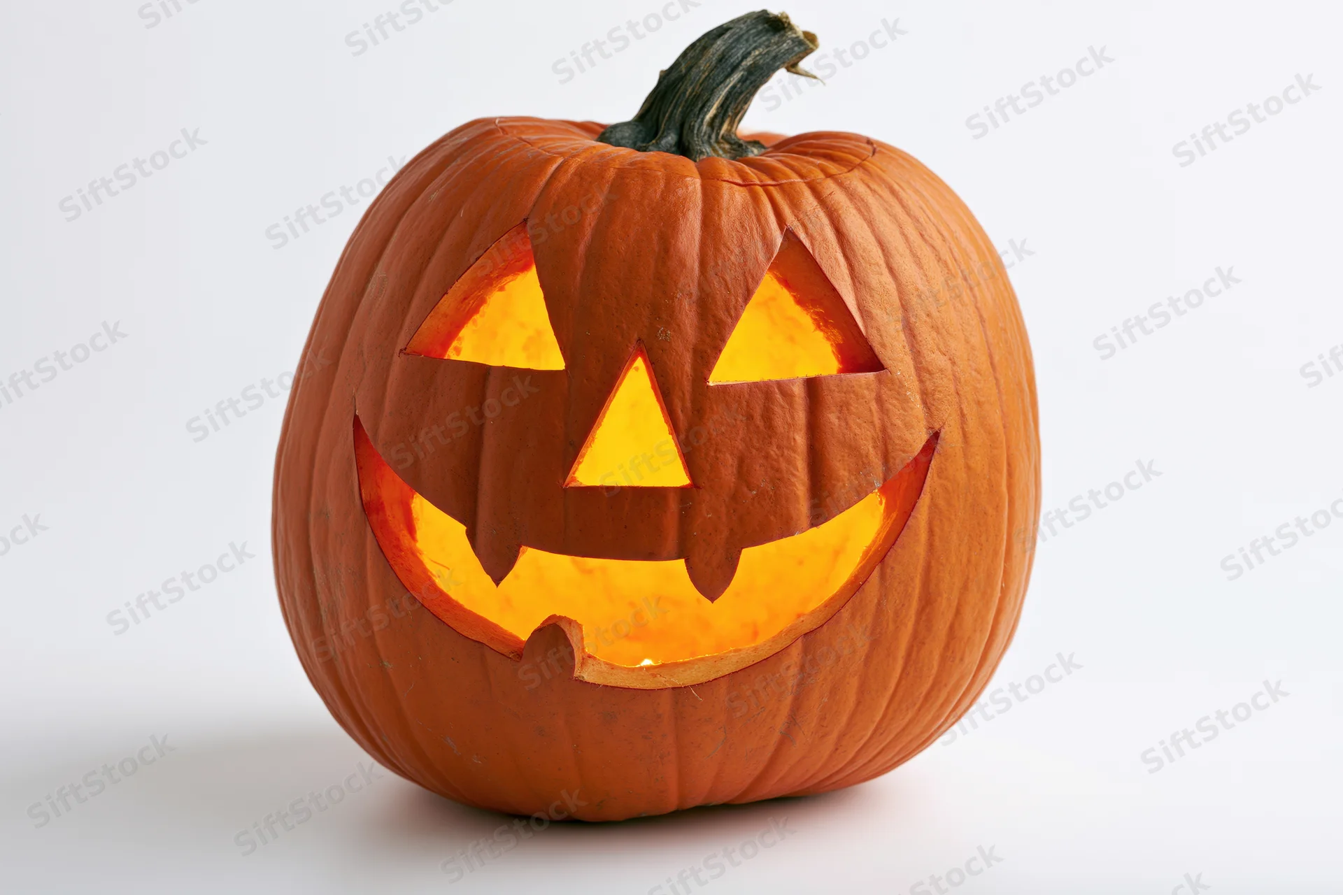 Carved pumpkin with glowing grin on white background