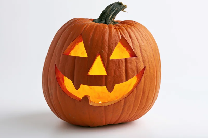 Carved pumpkin with glowing grin on white background