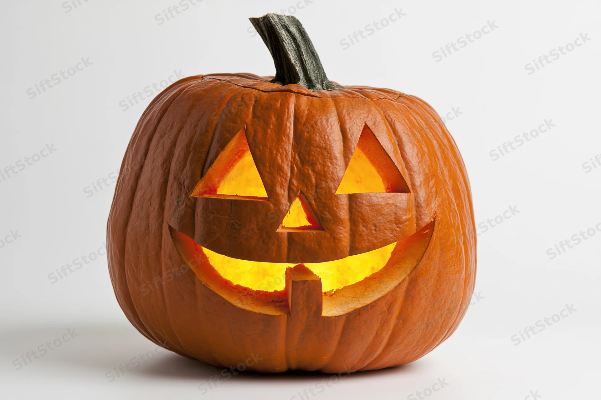 Carved pumpkin with glowing grin on white background