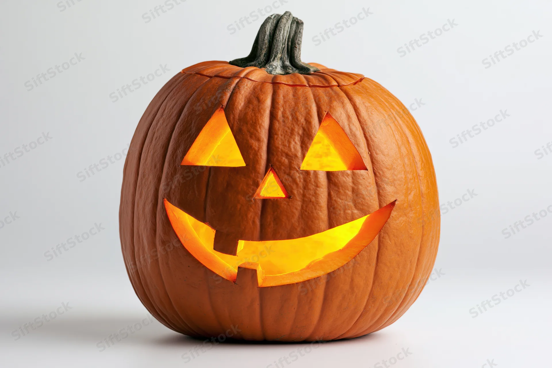 Carved pumpkin with glowing grin on white background
