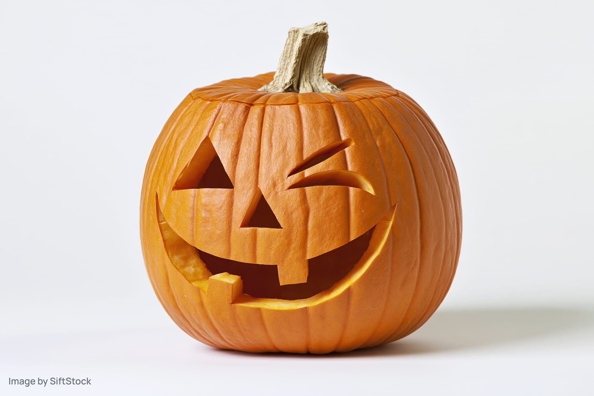 Carved pumpkin with grinning winking face on white background