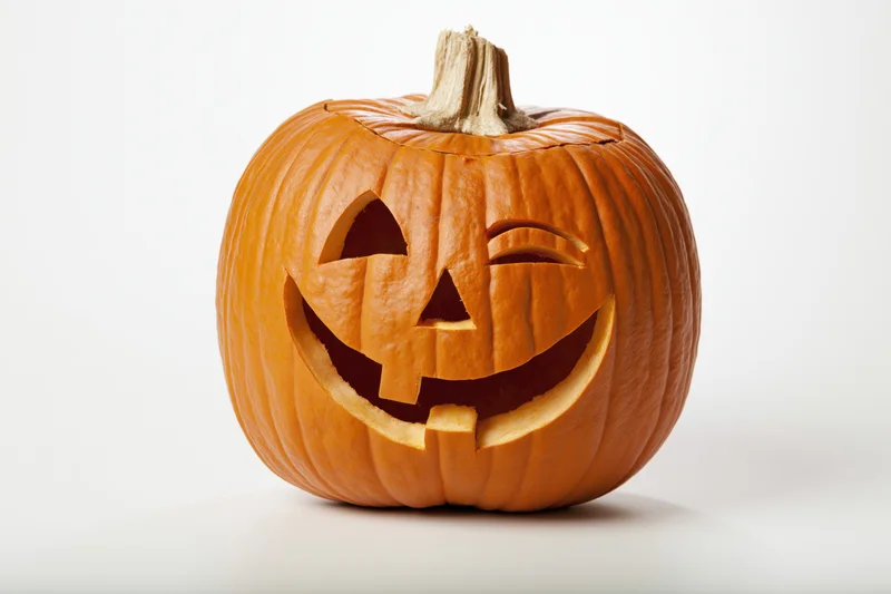 Carved pumpkin with grinning winking face on white background