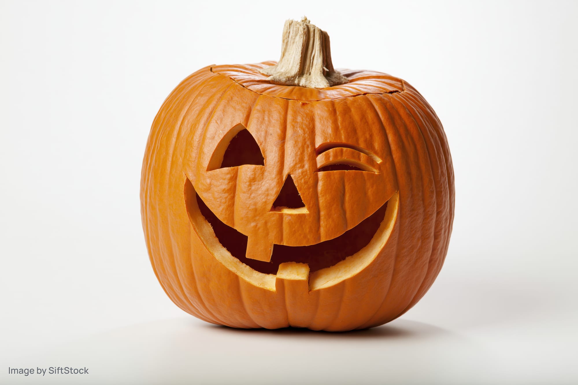 Carved pumpkin with grinning winking face on white background