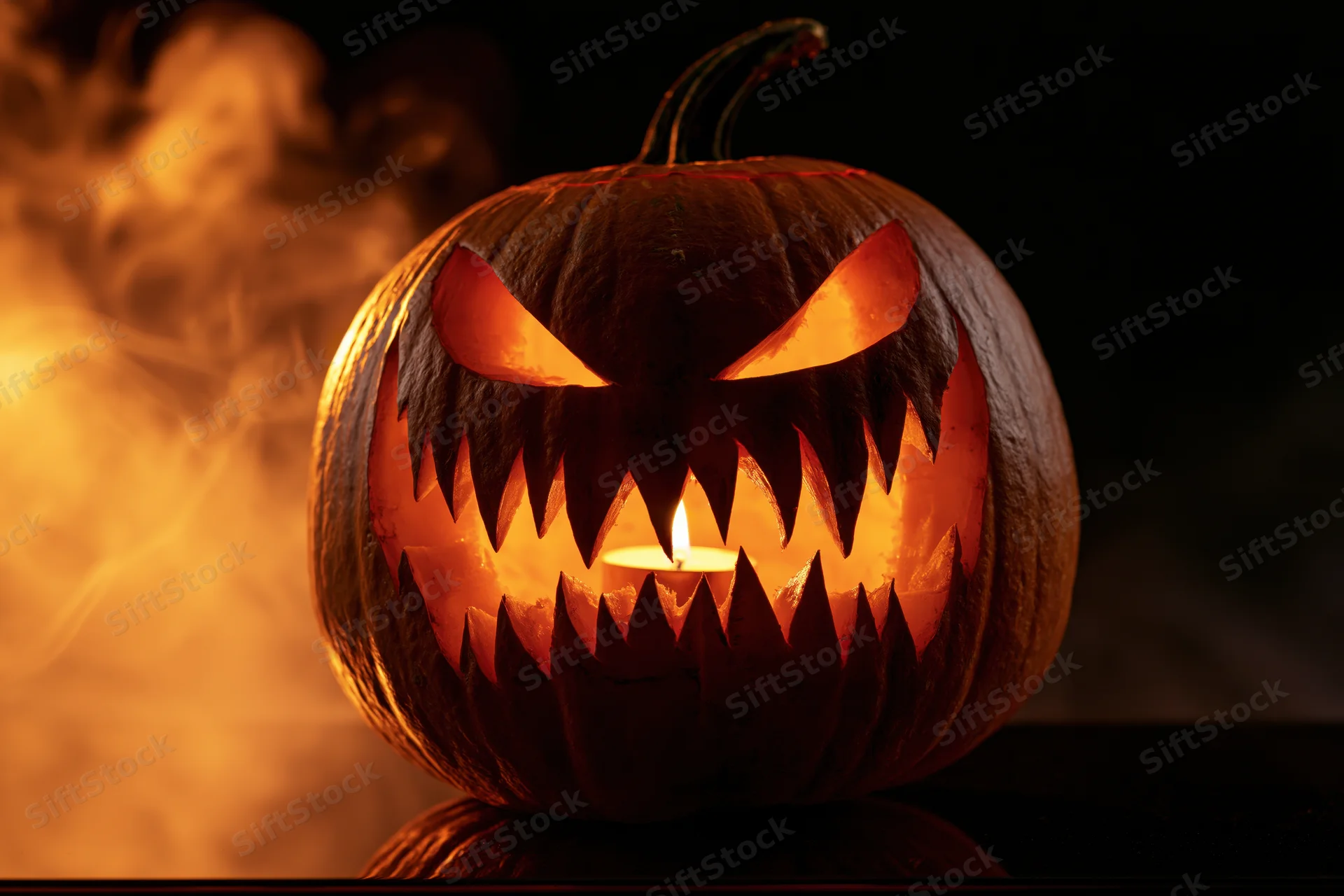 Carved pumpkin with jagged teeth and glowing eyes lit by candle, emitting smoke against dark background