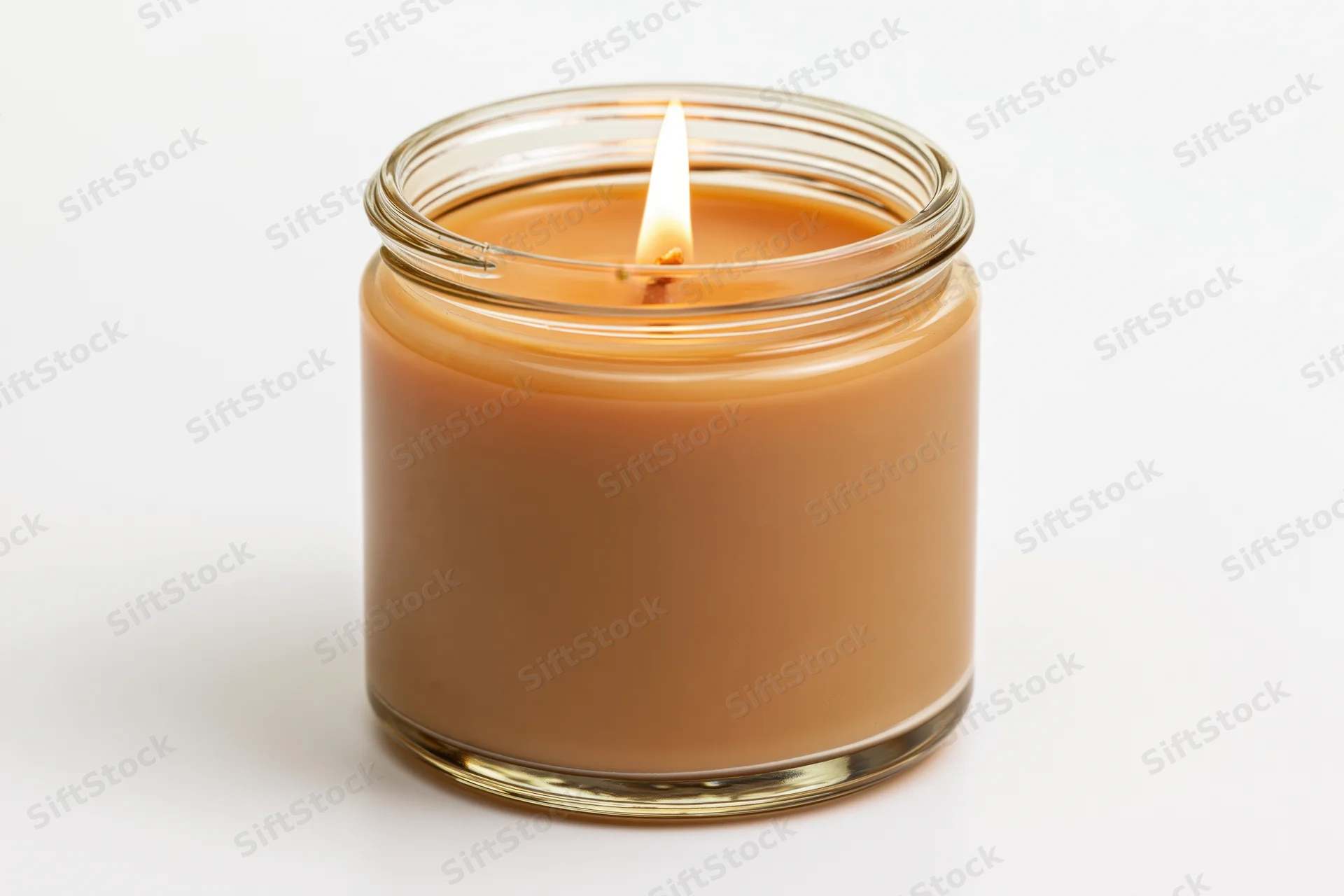 Lit soy candle in a clear glass jar glowing warmly against white background
