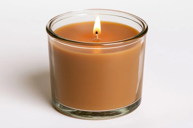 Lit soy candle in clear glass jar on white background