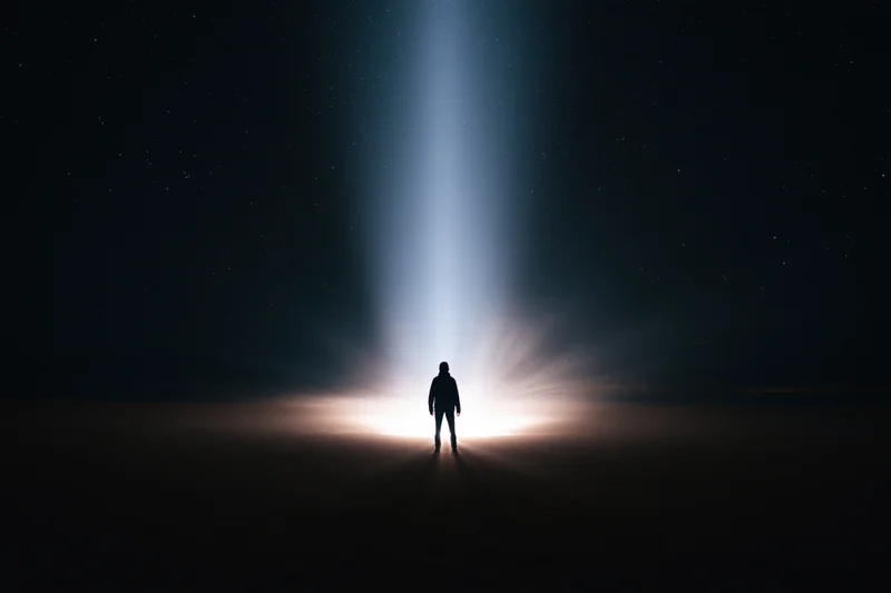 Silhouette of a person standing alone in the dark under a vertical beam of light at night