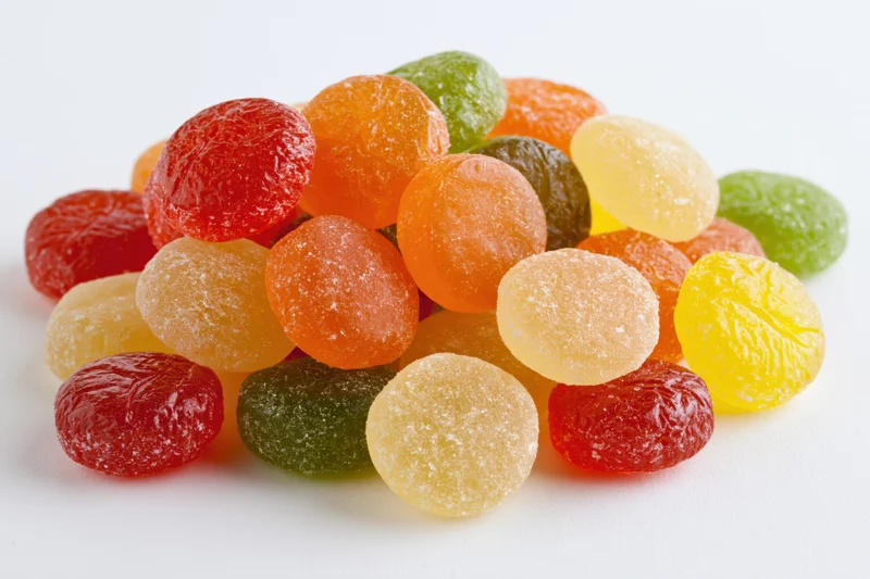 A pile of assorted colorful hard candy drops scattered on a plain white surface