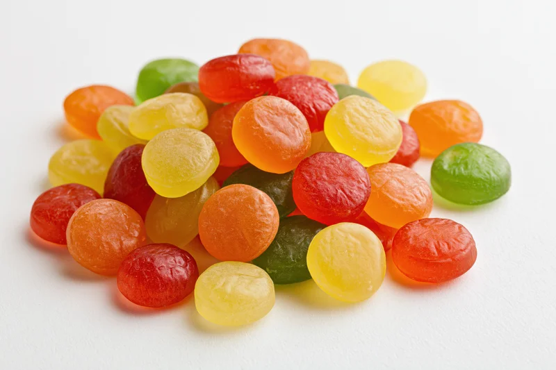 A pile of colorful hard candy drops scattered on a white surface
