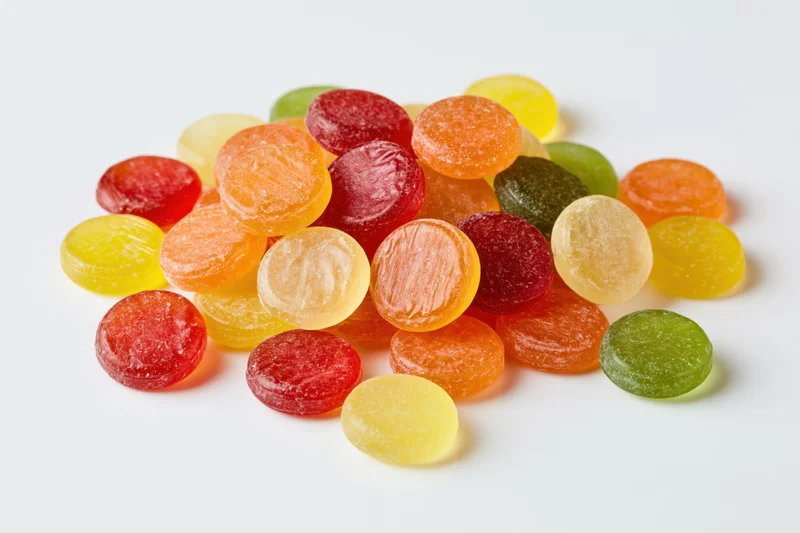 A pile of colorful round hard candies scattered on a white surface