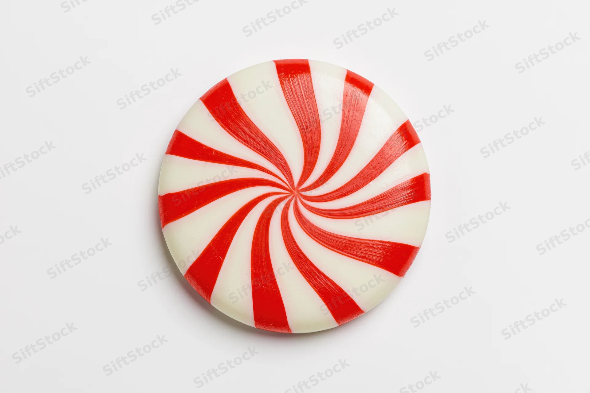 Round peppermint candy disc with red and white swirls on white background