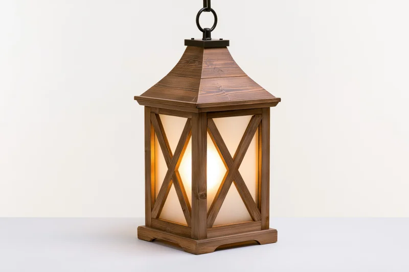 Rustic wooden lantern with x-cross glass panels glowing warmly on white surface