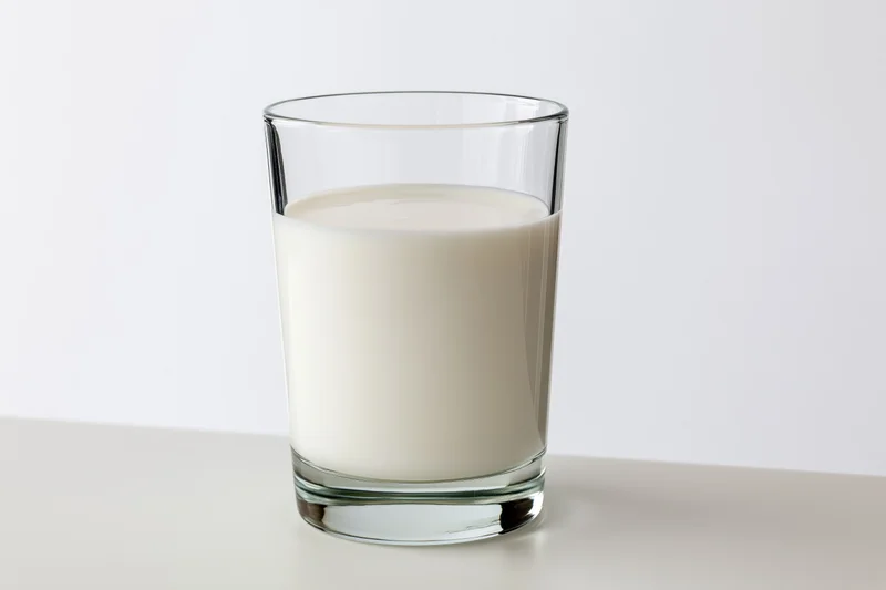 Glass of milk on a white surface in studio lighting
