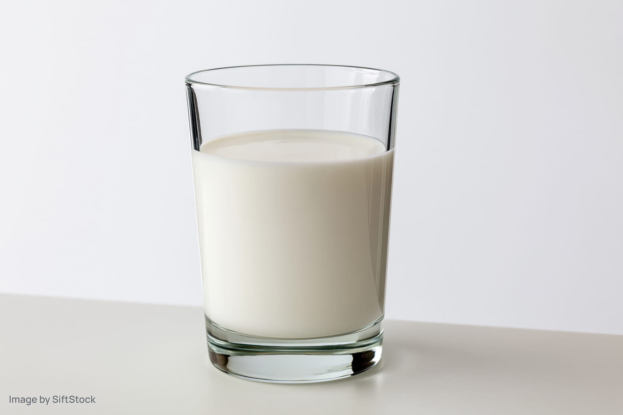 Glass of milk on a white surface in studio lighting