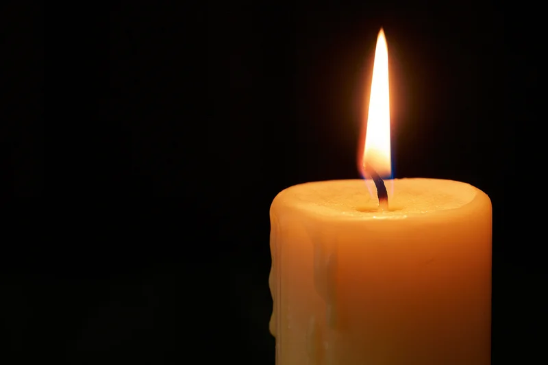 Lit candle burning against a black background