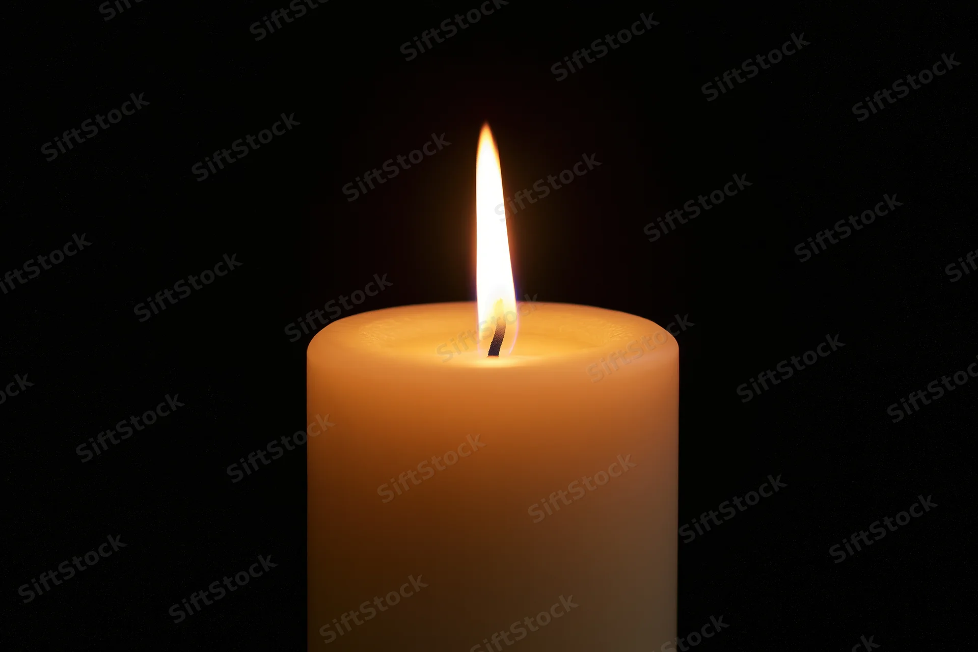 Single pillar candle burning with steady flame centered against black background