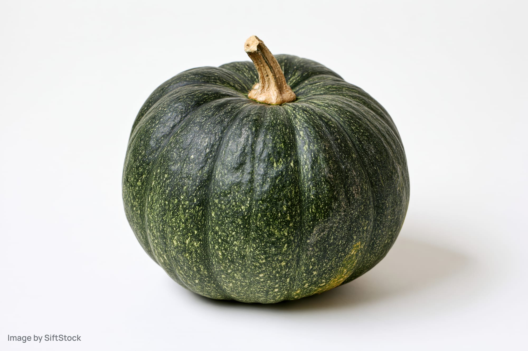 Whole kabocha squash with stem on white surface