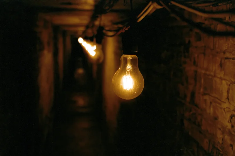 Glowing incandescent bulbs hanging in a narrow dimly lit brick tunnel