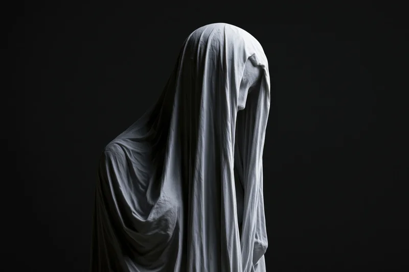 Veiled marble statue with head bowed against dark background