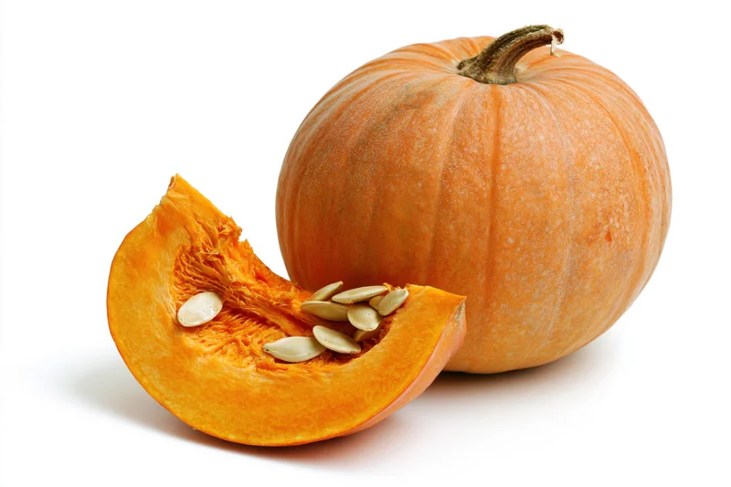 Whole pumpkin with a cut slice in front on white background