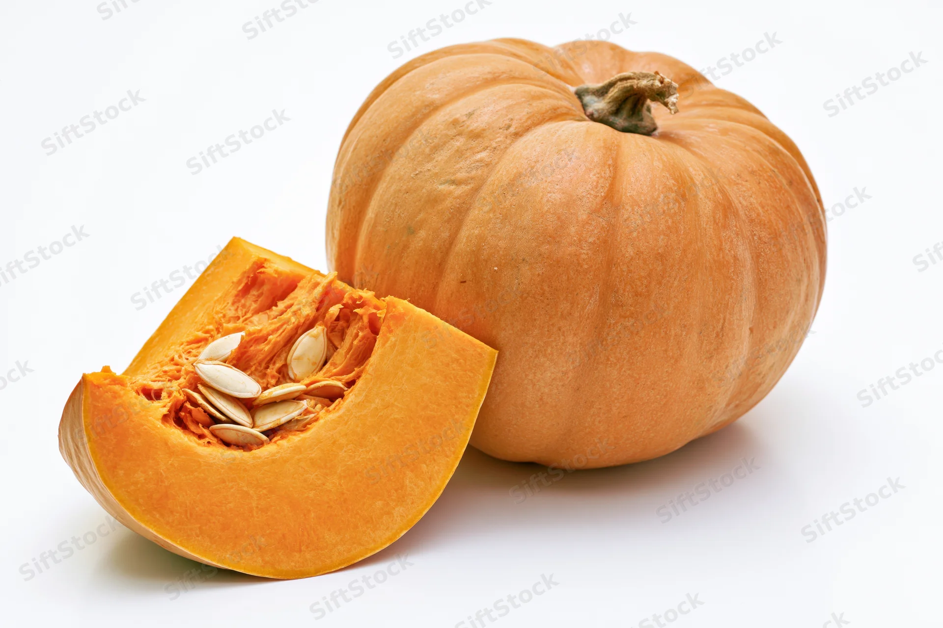 Whole pumpkin with a slice cut out and placed in front on white background