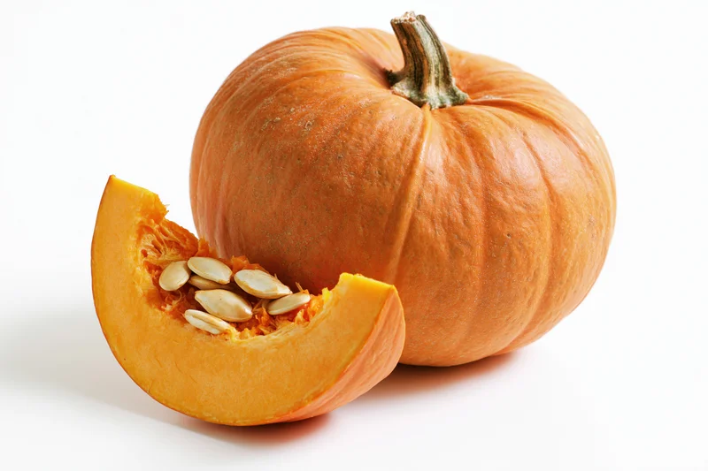 Whole pumpkin with a slice cut out and placed in front on white background