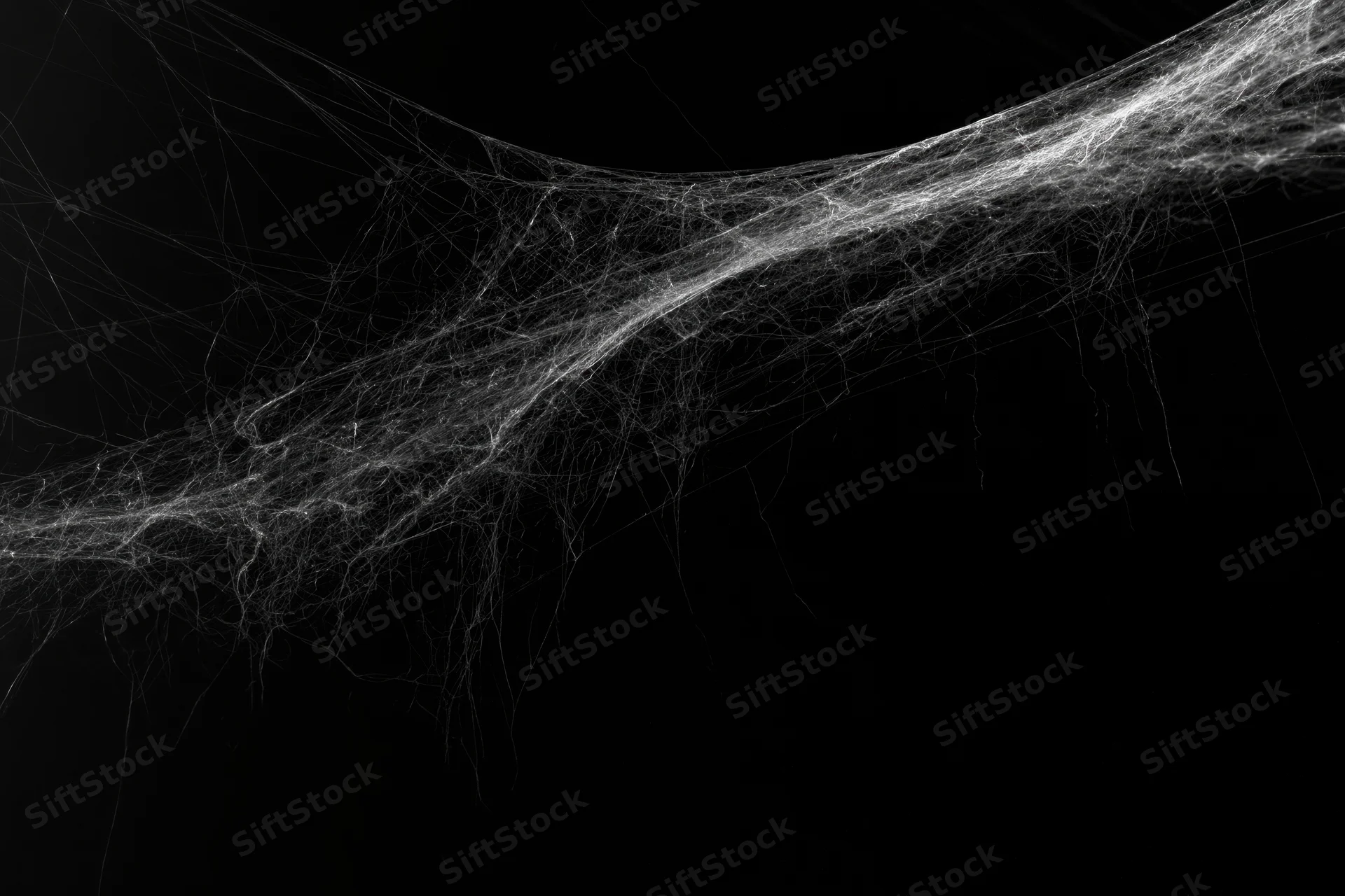 Abandoned spiderweb stretching across a dark corner with intricate threads and high contrast against black background