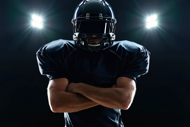 American football player with arms crossed under stadium lights